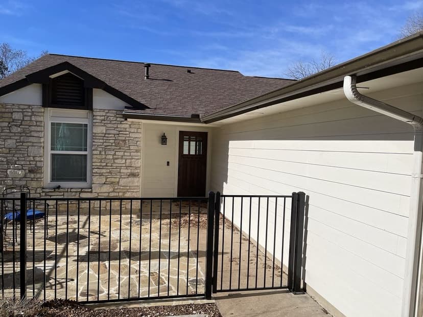 Ranch-style stone home with gutters and flagstone patio