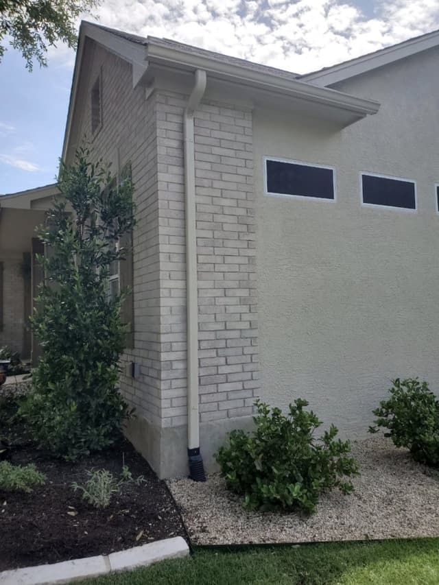 White downspout installation on brick home